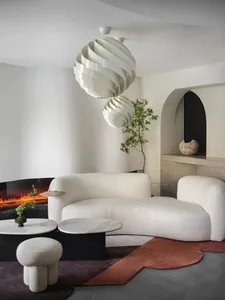 A modern white leather living room with a curved sofa, marble coffee table, and decorative lighting.