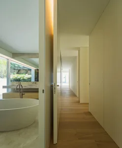 Modern minimalist bathroom with concrete walls, wood flooring, and a freestanding bathtub.