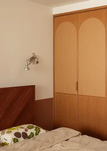 A minimalist bedroom with a wooden headboard and beige bedding and pillows.