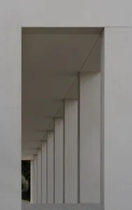 A modern architectural design featuring concrete columns and ceiling lights.