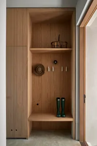A modern entryway featuring wooden shelves, a basket, a cowboy hat, and green rain boots.