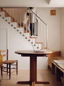 A modern home office featuring a wooden table, stairs, and a child climbing up the stairs.