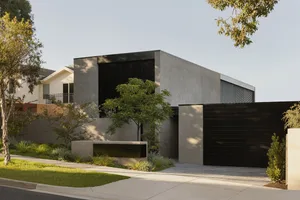 A modern house with a concrete exterior featuring large black windows.