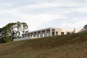 A modern house with a concrete exterior features large glass windows.