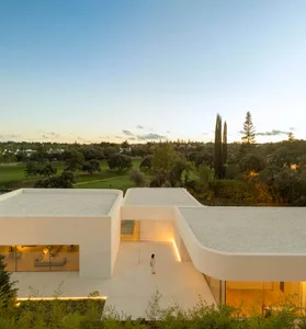 Modern house with concrete walls, glass windows, and gravel rooftop.