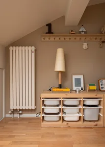 A modern interior design featuring a wood storage unit with white bins and a lamp on top, with a radiator and coat rack in th