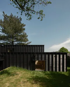 Modern minimalist house with wooden exterior and large glass windows.
