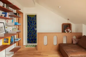 Modern minimalist living room with wooden shelves, a brown leather sofa, and glass window features.