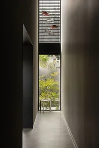 A modern residential interior with concrete walls, glass windows, and a view of a green courtyard.