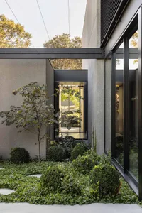Modern residential exterior featuring concrete walls and large windows.