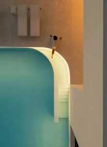 A modern swimming pool with a concrete edge, illuminated lighting, and glass elements.