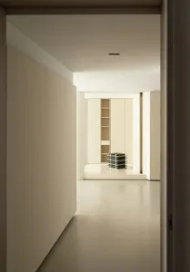 A minimalist interior space featuring cream-colored walls and an open floor plan.