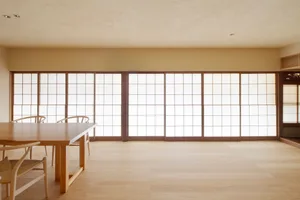 Minimalist residential dining room featuring wooden furniture and a large sliding glass door.