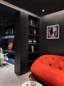 A modern living room with black paneled walls, a red sofa, and a sleek, minimalist design.