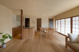 A modern, contemporary kitchen dining room with wooden furniture and cabinets, featuring a long wooden dining table with chai