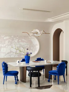 Modern dining room with a marble table, blue velvet chairs, and decorative lighting.