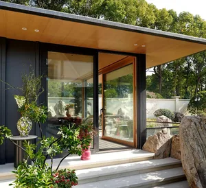 Modern residential exterior with glass doors, timber accents, and stone elements.