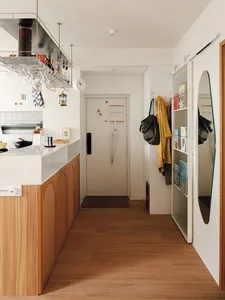 A modern kitchen featuring a wooden countertop with white appliances and various kitchenware hanging above.