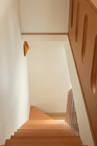 現代室內設計，木質樓梯搭配鋼製扶手，白牆與木地板，牆面燈光營造氛圍