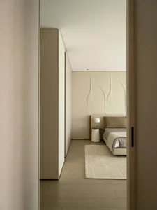 A neutral-colored minimalist bedroom with a textured fabric upholstered bed and white accent table.