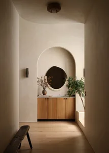 Minimalist entryway featuring a round mirror, wooden cabinet, and marble countertop.