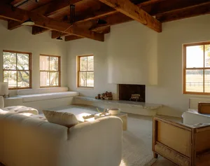 A minimalist living room with white furniture and a brick wall.