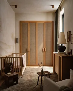 A modern nursery with wooden furniture, a crib, a wardrobe, and various decorative items.