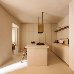 Modern, minimalist kitchen featuring a central marble island with a stove and seating area.