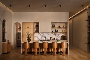 Modern minimalist kitchen featuring marble countertops and wooden cabinets and stools