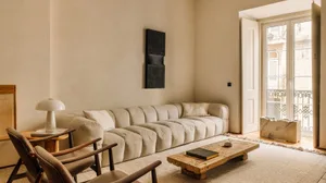 A minimalist living room featuring a fabric sofa, wooden coffee table, and marble accents.