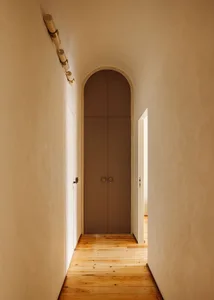 Hallway with a modern storage cupboard featuring concrete walls and wooden flooring.