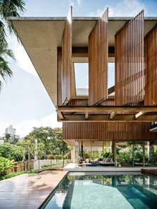 Modern house exterior with wooden slat facade, glass walls, and concrete roof.