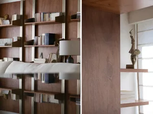 Modern, minimalist interior with wood shelves containing books and sculptures.