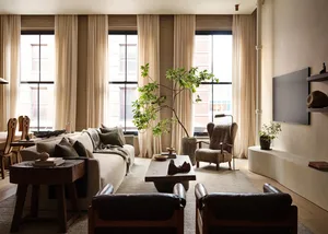 A modern living room with a large sofa, armchairs, wooden tables, and a television on a low unit.