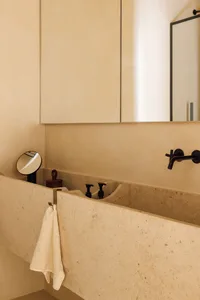 Photo of a retro bathroom featuring a marble sink and countertop with a black faucet and two soap dispensers.