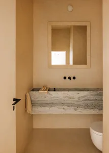 Minimalist bathroom with a marble countertop, white sink, and beige walls.
