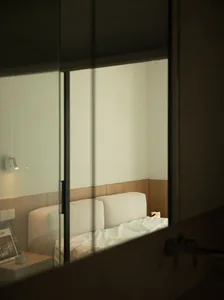A minimalist bedroom with a fabric bed and wooden accents.