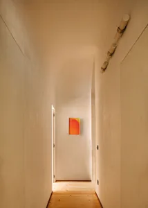 A minimalist hallway with smooth plaster walls and a wooden floor.