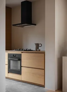 A minimalist kitchen with wooden cabinets and black appliances.