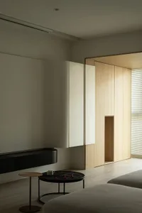 A minimalist living room featuring wooden furniture, glass walls, and concrete surfaces.