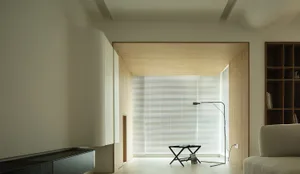A minimalist living room featuring wooden walls, glass windows, and metal furniture.