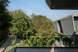 A modern house with concrete exterior overlooking a lush garden.