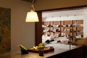A modern living room with a library area, featuring a white sofa, bookshelves, and a wooden divider.