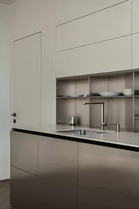 Modern minimalist kitchen with stainless steel cabinets and countertops. Open shelving and sleek design.