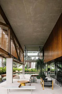 Modern residential interior with concrete and wooden materials, featuring a lounge area, pool, and outdoor seating.