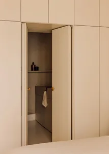 A minimalist living space with a hidden room revealed through a single door, featuring a concrete interior.