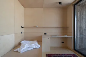 A minimalist living room with wooden walls, shelves, and a desk.