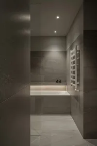 Modern bathroom designed with concrete tiles, featuring warm lighting and minimalist decor.