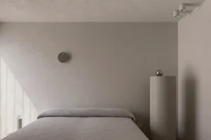 A modern bedroom with concrete walls and a minimalist bed.