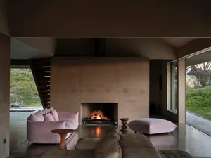 A living room with modern furniture and a large concrete fireplace.